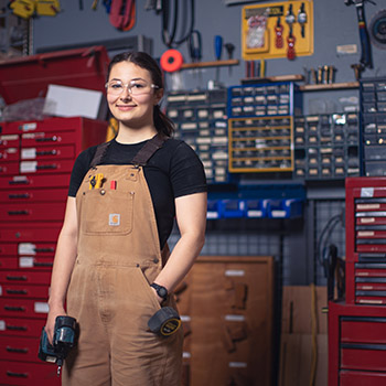 Hilary stands in a carpentry workshop.