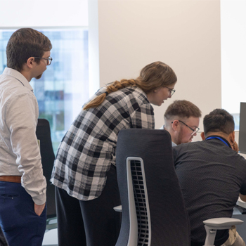 Image shows a group of students gathered around a computer.