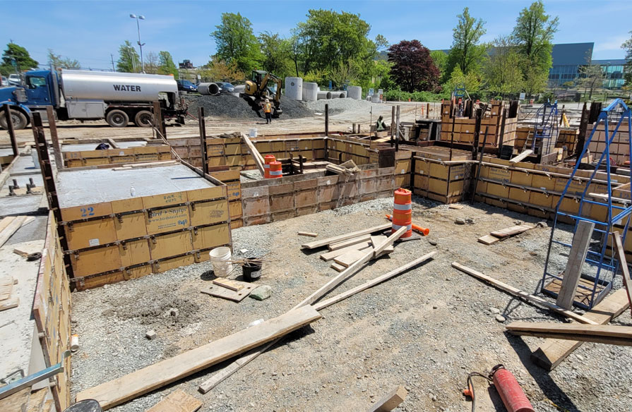 An outdoor construction site is shown. The ground is dug and the ground is prepped to be laid.