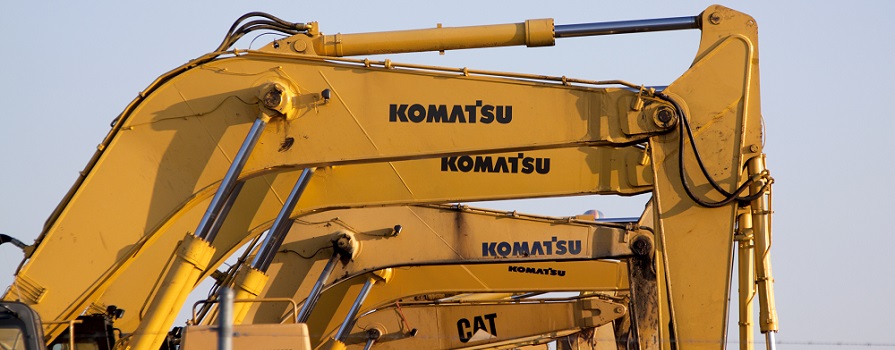 A portion of the buckets of several Komatsu- and CAT-brand tractors are shown.