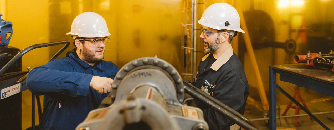 Image of an NSCC Pipe Trades student and their faculty working together in a classroom shop setting.