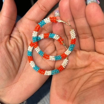 A pair of beaded earrings laying in someone's hands.