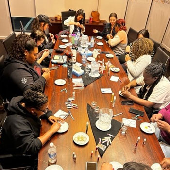 Students sit around a table beading.