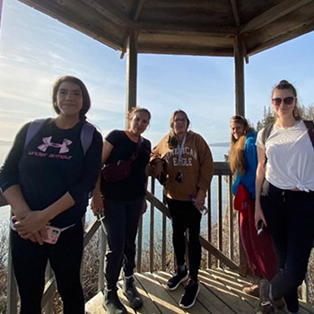 Students stand at in a gazebo overlooking the ocean.