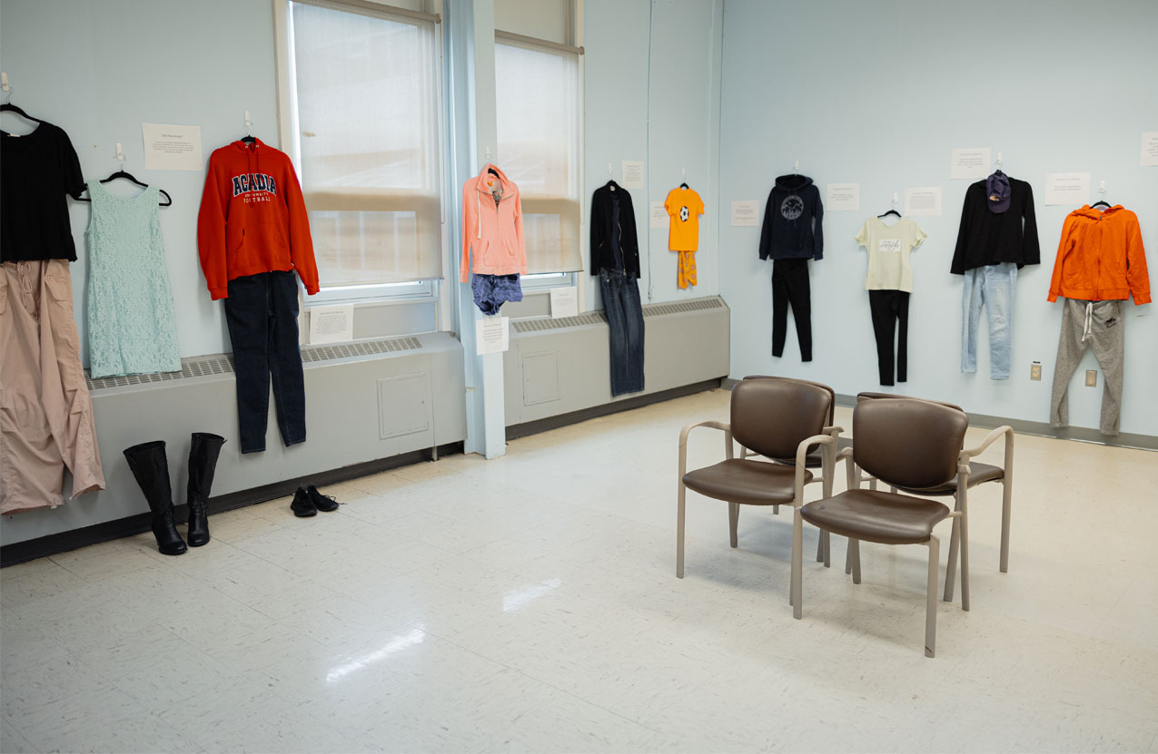 A classroom has multiple outfits hanging on the wall during an exhibit.