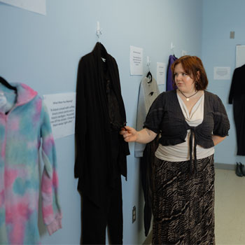 A student is looking at an outfit that is on display at the exhibit at Lunenburg Campus.
