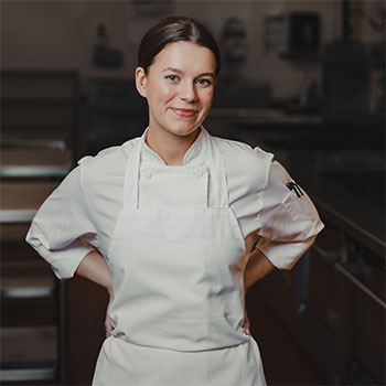 A person wearing a chef uniform is posing for a photo.
