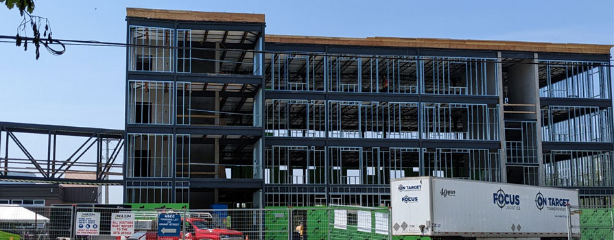 From the road, a new student housing building is being built. The wall framing is complete and ready for the next steps.