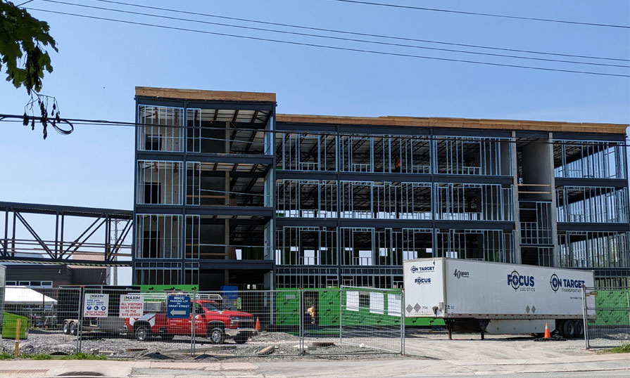 From the road, a new student housing building is being built. The wall framing is complete and ready for the next steps.