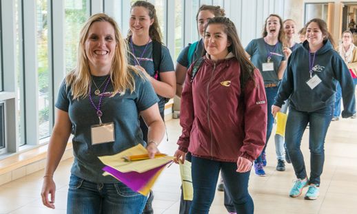 Image shows a woman walking down a bright hallway with students walking behind her.