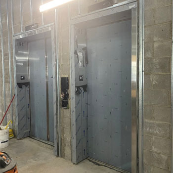 Image shows freshly installed elevators within a new building currently under construction.