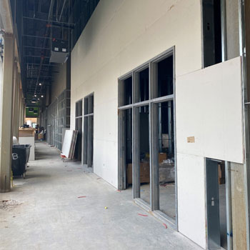 Image shows the inside of a building that is under construction. The walls are freshly dry walled and ready to be painted. 