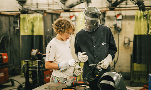 A youth with welding instructor in a trades shop