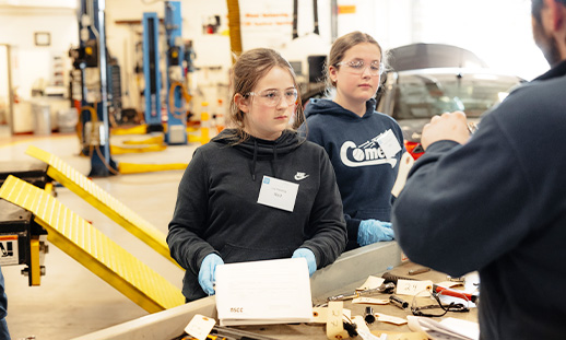 Two youth in a trades classroom learning from an instructor