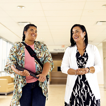 Zena Jarvis and Shawnee Sylliboy walk side by side inside an NSCC Campus.