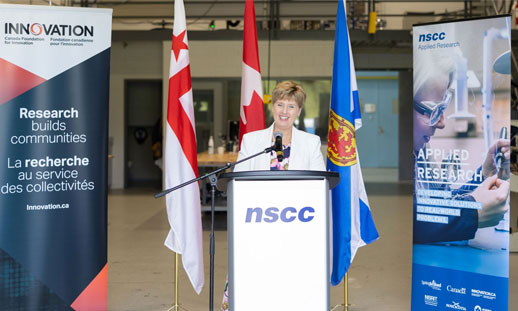 A person is standing at a podium giving an announcement in a trades classroom.