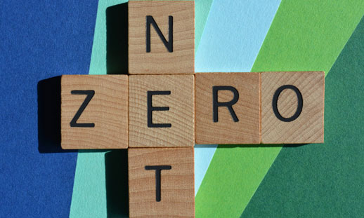 Scrabble letters read 'net zero' on a blue and green background.