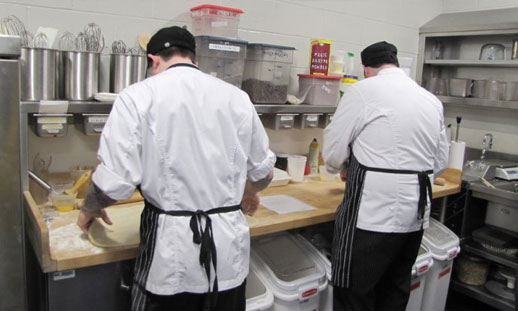 Student chefs cooking in a commercial kitchen.