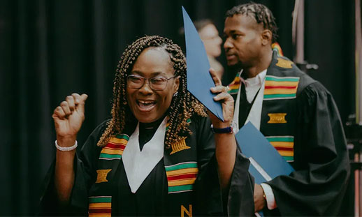 A person is celebrating at graduation, holding their diploma in their hand.