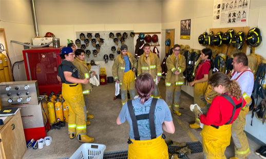A group of youth are pulling on firefighter gear.