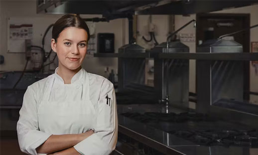 A chef is standing in a kitchen.