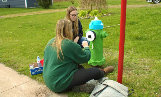 Paige and Madison McLaughlin touch up a fire hydrant in Stellarton as part of NSCC's work in the community.