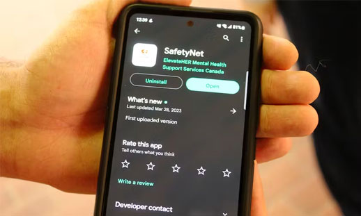 A hand is holding a phone, open to the App Store prompting you to download the new 'SafetyNet' app, an app to help prevent human trafficking.