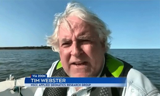 A man is sitting on a boat in the ocean giving an interview to a news host.