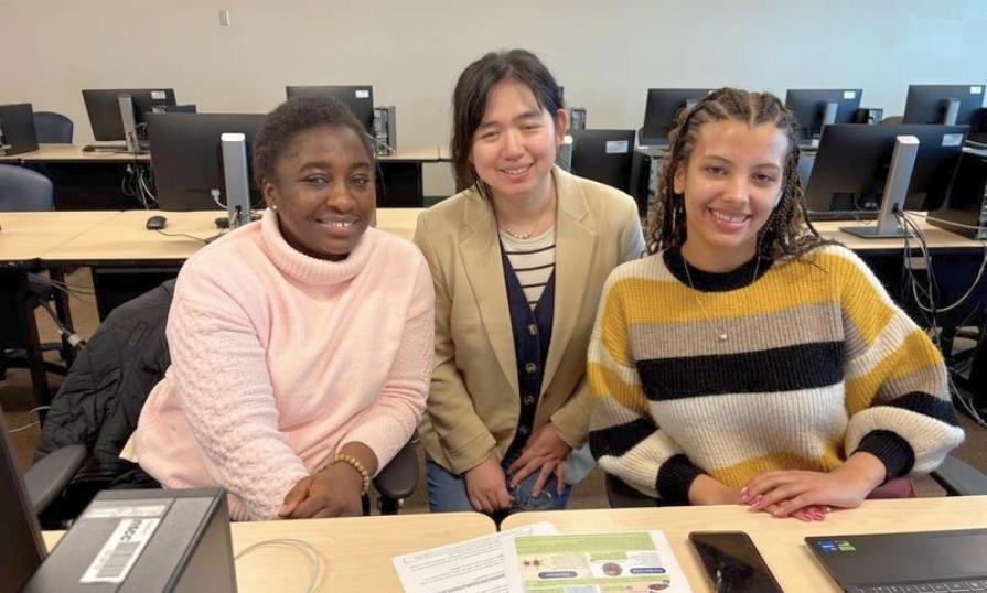 Three women in a classroom setting smiling for photo.