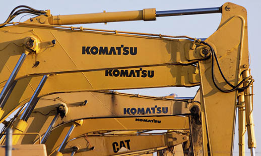 A portion of the buckets of several Komatsu- and CAT-brand tractors are shown.