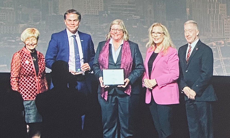 Don Bureaux, NSCC President and Katie Orr, Director of NSCC International pose with 3 others, holding an award and a framed certificate as they receive the Global Excellence Award.