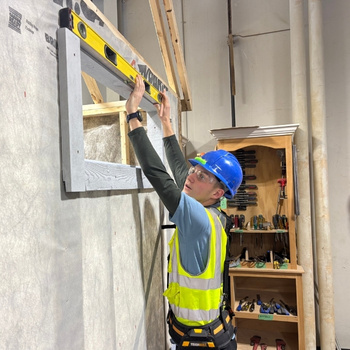 Ethan uses a level to check the trim on a shed window.