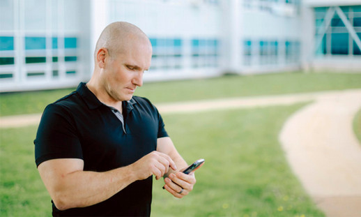 A person is standing outside looking at their phone.