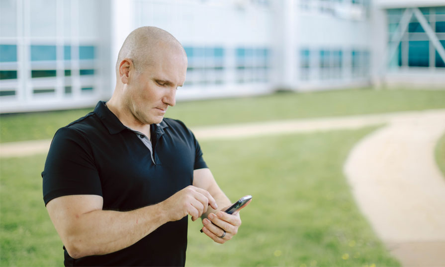 A person is standing outside looking at their phone.