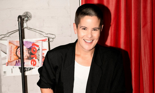 A person standing in front of a curtain smiling. 