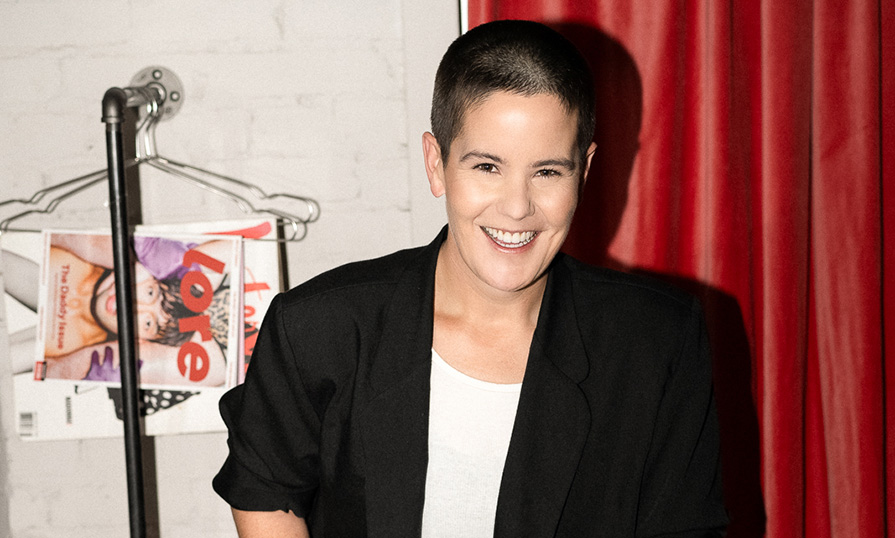 A person standing in front of a curtain smiling. 