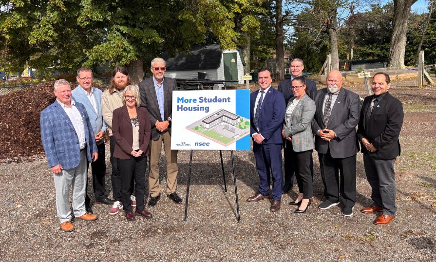Image of ten individuals from NSCC Kingstec Campus and the Nova Scotia Government standing in front of the future home of new student housing at Kingstec Campus.