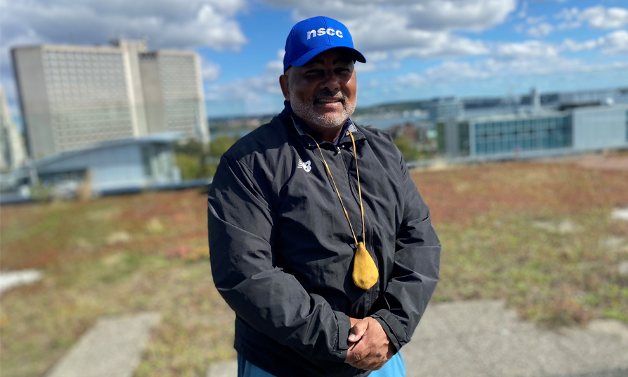 Person with arms crossed standing in front of the Halifax harbour.
