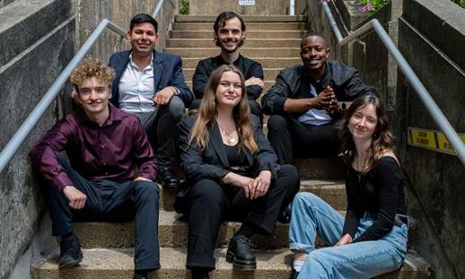 Six Music Business students sit on a set of stairs outside. 