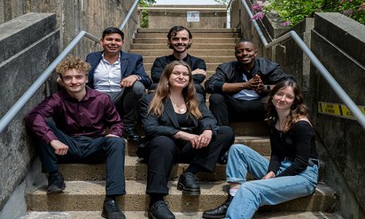 Six Music Business students sit on a set of stairs outside. 