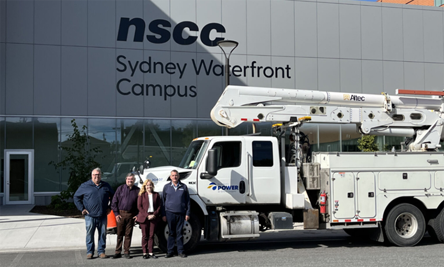 Four people and a Nova Scotia Power truck in front of NSCC Sydney Waterfront Campus.
