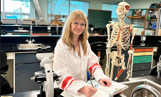 Student standing in a lab wearing a lab coat