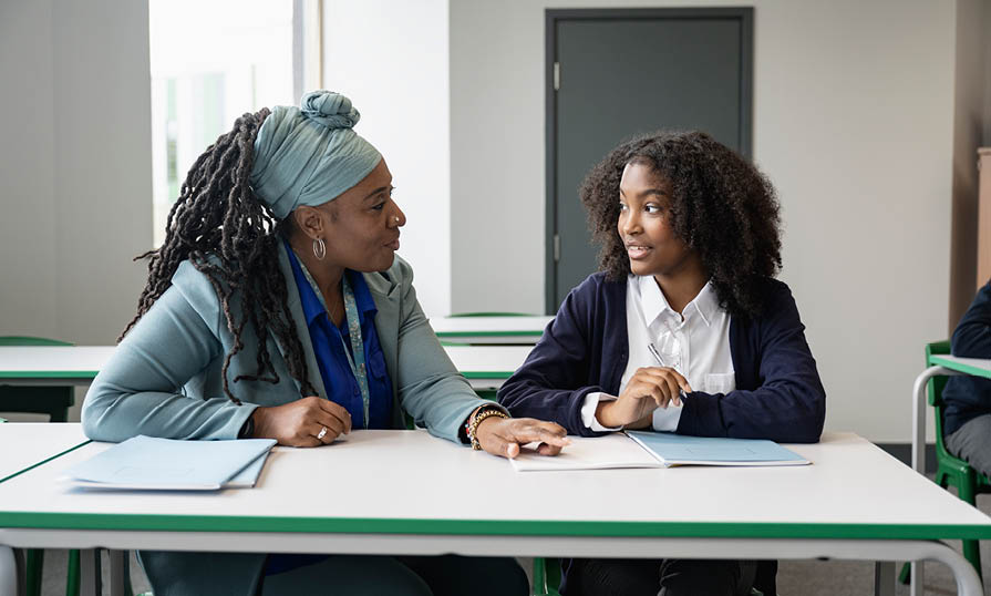 A teacher working with a student at a table. 