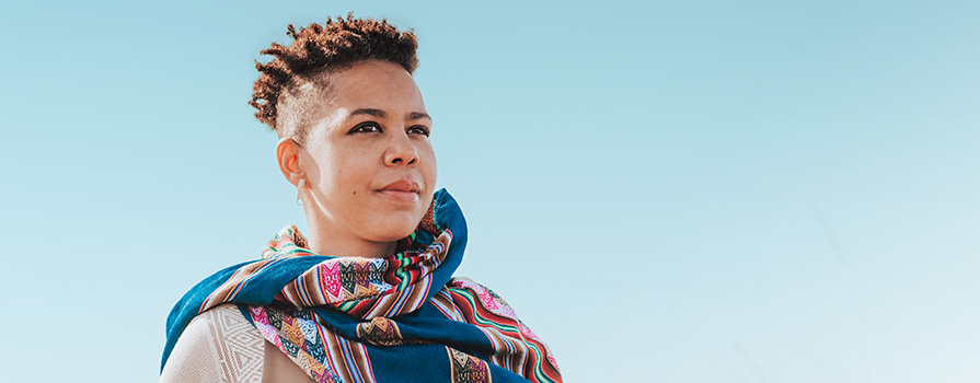 A woman with a floral scarf looks out over the horizon.