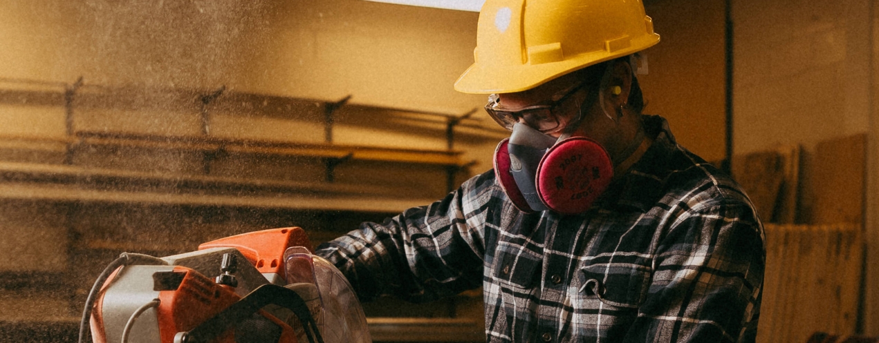 An NSCC student wears a respirator while using a mitre saw in a carpentry shop.