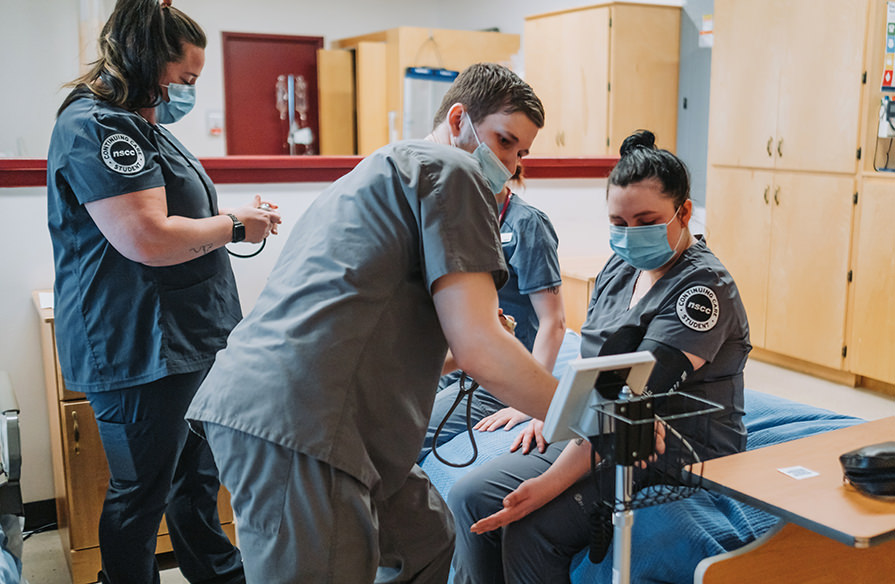 Nursing students practice taking blood pressure on one another. 