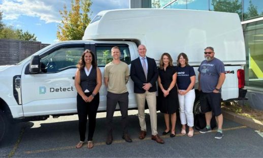 A group of professionals stand together for a photo in front of a parked van with a Detect logo.