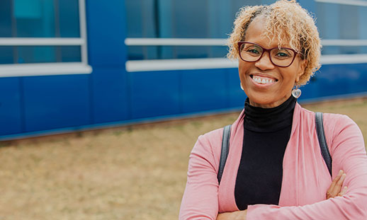 A smiling woman stands facing the camera.