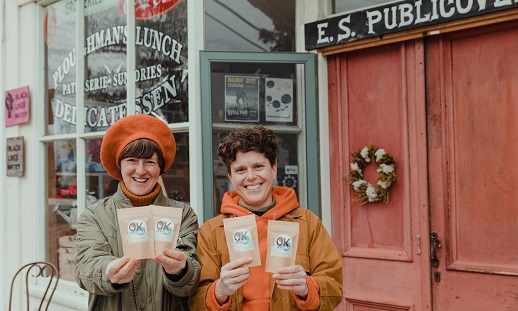Kim Kelly, an NSCC student, and her partner Onya Hogan-Finlay smile near a storefront while holding packages of sea salt.