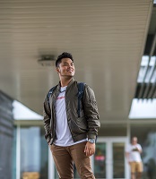 A student stands in front of NSCC Ivany Campuses main entrance and gazes over his left shoulder.